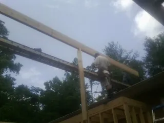 Carpenter setting a ridge beam over a new addition frame — Ice Dam Removal by Roofing Brothers in Cinebar