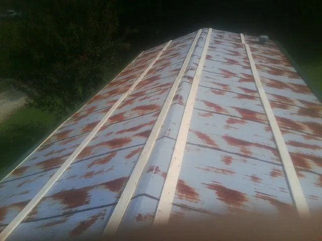 Rusted metal roof panels with new wood purlins before replacement — Storm Damage Roof Repair in Cinebar by Roofing Brothers