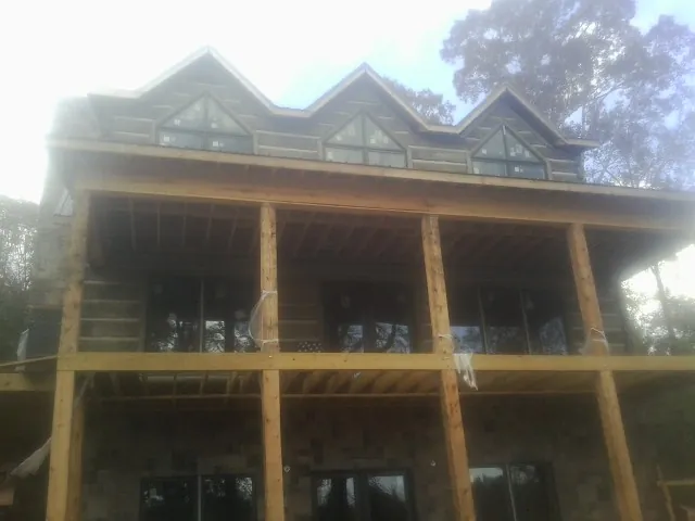 Dormers and porch framing on a large log home under construction — Roof Coating work by our crew in Cinebar