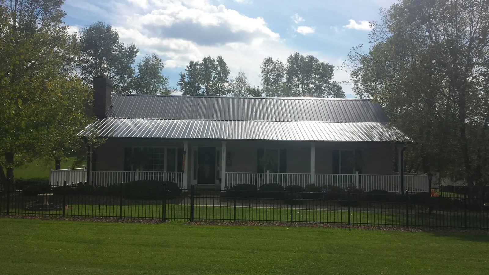 Gray metal roof on a brick ranch with a full width front porch — Gutter Guard Installation work by our crew in Cinebar