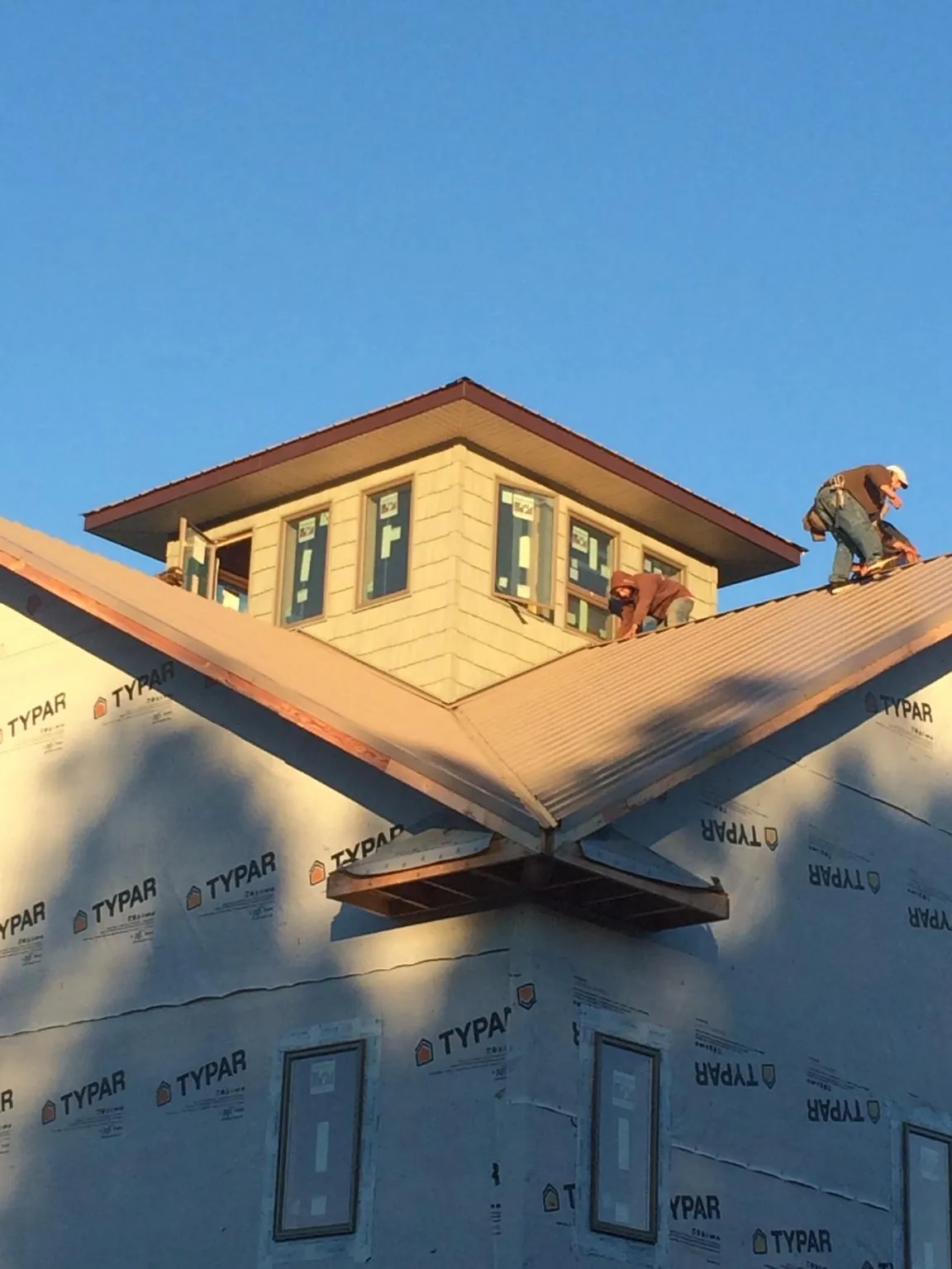 Roofers working around a rooftop cupola on a new metal roof at sunset — Roof Waterproofing in Cinebar by Roofing Brothers